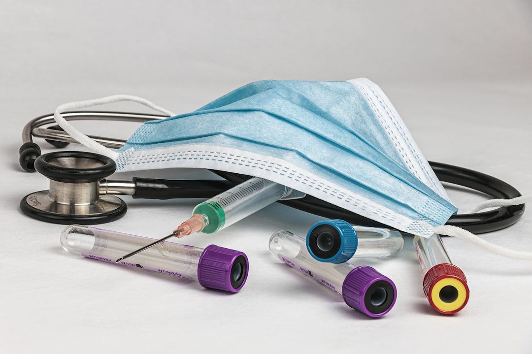 A stethoscope, medical mask, and various laboratory test tubes scattered on a white surface