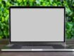 a laptop on a wooden table with a blurred green background