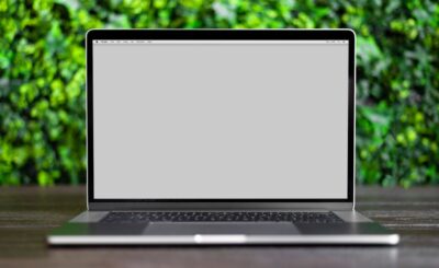 a laptop on a wooden table with a blurred green background