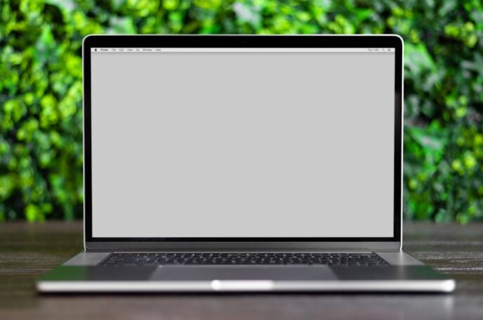 a laptop on a wooden table with a blurred green background